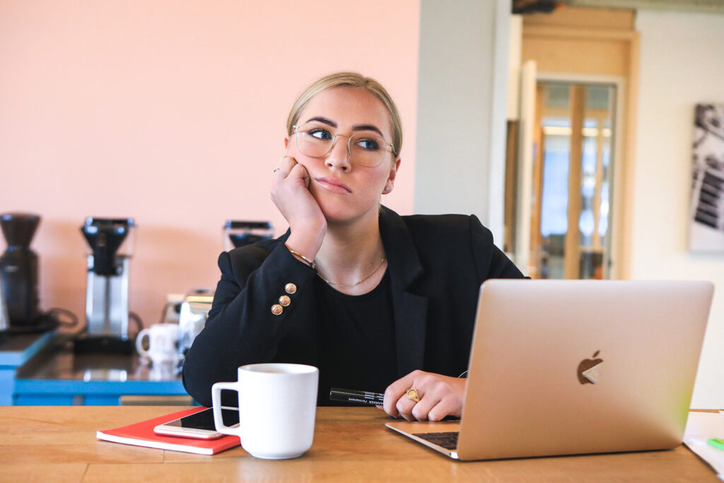 Woman looking bored next to her Macbook laptop.